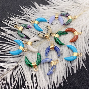 Natural stone crescent pendants with gold rings displayed on white feathers