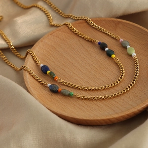 Retro bohemian gold titanium necklace with multi-color natural stone beads on a wooden tray