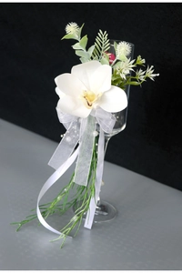Close-up of white cymbidium orchid with organza ribbons on wedding toast wine glass