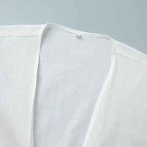Close-up of a white cotton linen top neckline with size S label and natural fabric texture