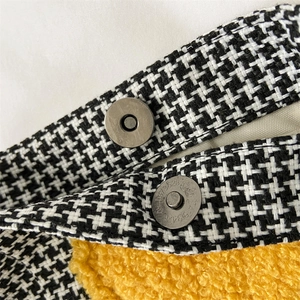 Détail du tissu pied-de-poule avec doublure polaire jaune et boucle magnétique argentée