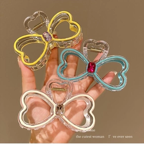 Detailed close-up of bow-shaped hair clips with colorful acrylic edges and large crystals