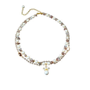 Double-layered gold necklace with white pearls, purple crystals, and a floral pearl pendant