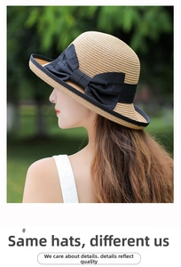 Detail of a beige woven straw sun hat featuring a large black bow and fine mesh texture