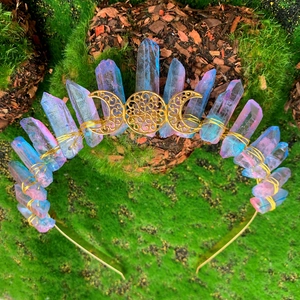 Macro view of blue-pink natural crystal crown with gold triple moon on mossy wood