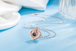 Detail of rose gold double heart necklace with LOVE engraving and central crystal inlay
