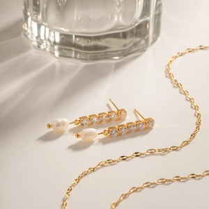 Detail of gold zircon earrings with freshwater pearls and matching elegant necklace