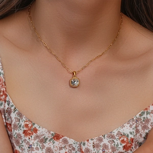 Detail of a paperclip chain necklace with a square zircon pendant worn by a model