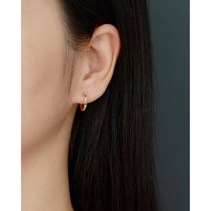 Close-up of a gold huggie earring featuring colorful rhinestones on a female model