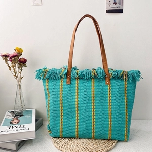 Bohemian woven beach tote bag with green stripes, tassels, and brown shoulder straps