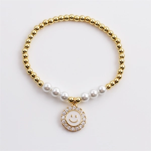 Detail of beaded bracelet featuring gold copper beads, white pearls and a zircon smiley face charm