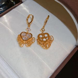 Detail of gold heart earrings featuring sparkling zircons and delicate long metal tassels