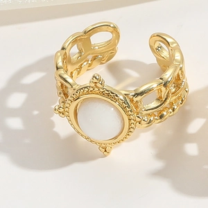Detailed macro view of a gold-finish ring featuring a white gemstone and woven texture