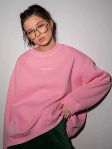 Close-up of oversized pink sweatshirt showing crewneck detail and maskin letter print