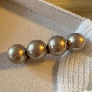 Detailed view of four large champagne gold pearls on a linear metal hair clip base