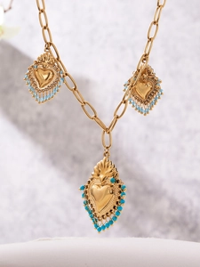 Détail de pendentifs cœur dorés avec des perles turquoise sur une chaîne en métal