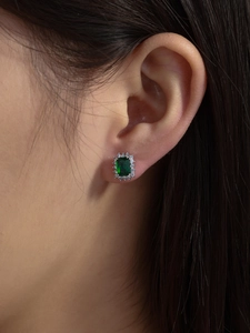 Detail of emerald green rectangular stud earring with white halo stones on model