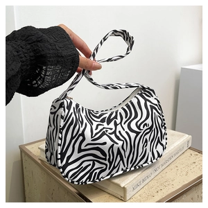 Détail du mini sac baguette en toile à motif zèbre avec texture textile et bandoulière