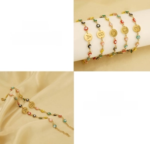 Detail of gold titanium steel bracelet with evil eye beads and letter charms