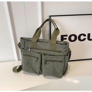 Close-up of army green corduroy tote bag featuring two front zipper pockets and top handles