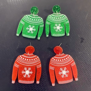 Detail of red and green Christmas sweater earrings with snowflakes and glitter powder