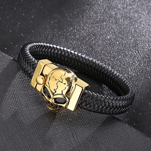 Detail of black braided leather bracelet with golden skull magnetic clasp closure