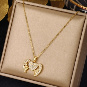 Detailed close-up of golden heart and wing pendant necklace on champagne jewelry box