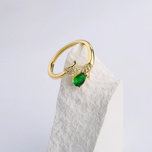 Luxurious gold leaf ring featuring a pear-cut green gemstone on a white mineral stone