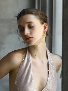 Close-up of gold flower stud earrings with elegant pearl tassels worn by a model