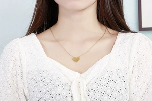 Close-up of a double-layered gold heart necklace with MOM pendant on a female model