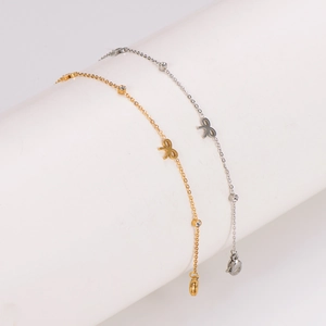 Elegant gold and silver bow anklets with sparkling zircon accents on white pedestal