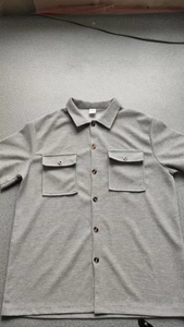 Close-up of gray waffle knit shirt texture with dual chest pockets and lapel collar details