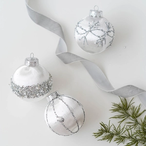 Elegant white satin Christmas ball set with silver sequins and pearls on pine branch