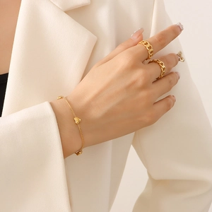 Golden heart pendant bracelet and matching rings set on a model in beige suit