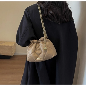 Quilted khaki chain bucket bag shown on shoulder for a stylish look and practical use