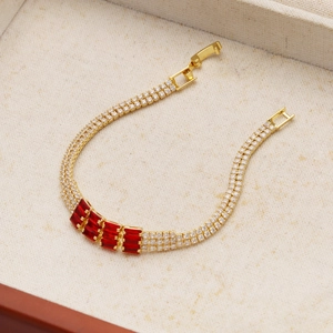 Dettaglio di bracciale dorato con quattro gemme rosse rettangolari e doppia fila di zirconi