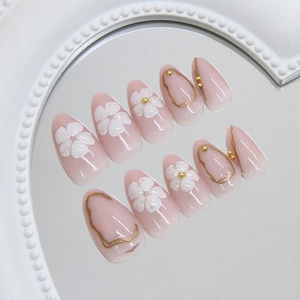 Elegant 3D flower almond press-on nails with gold accents and translucent pink base
