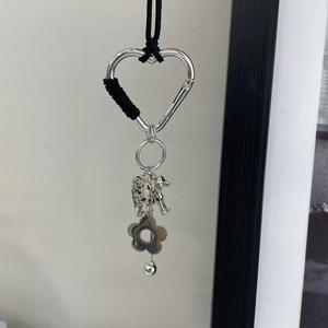 Détail d'un mousqueton cœur argenté avec pendentifs chien, fleur et cœur taché