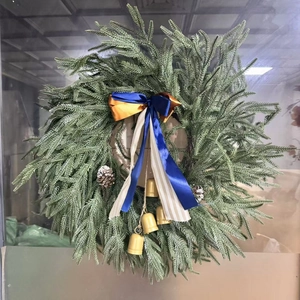 Close-up of artificial Christmas wreath with blue bows, pine cones, and gold bells