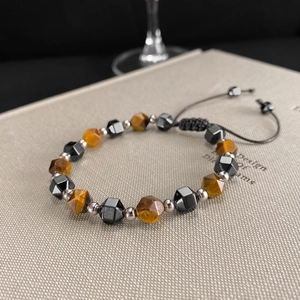 Tiger eye and obsidian beaded bracelet with woven cord on a textured book surface