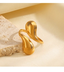 Macro detail of golden double teardrop open ring with polished finish on stone background