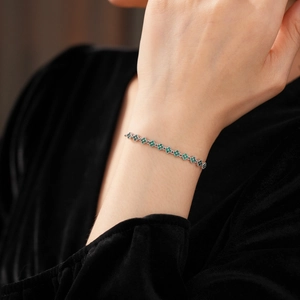 Close-up of sparkling green clover gemstone bracelet set in polished silver on a wrist