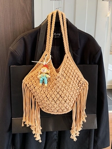Khaki handwoven tote bag with fringe tassels and diamond pattern on a black blazer