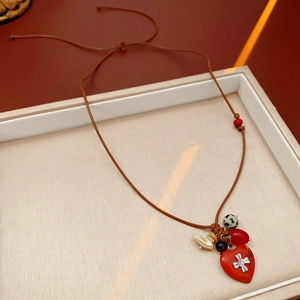 Close-up of red heart pendant with silver cross and colorful beads on a wax cord