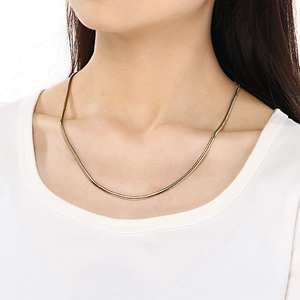 Golden stainless steel flat snake bone chain necklace worn by a female model
