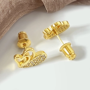 Macro shot of gold double heart stud earrings with white zircon paving and metal backs