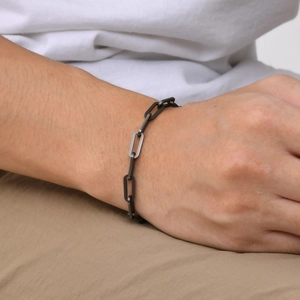 Close-up of men's matte black geometric chain bracelet with rectangular links on wrist