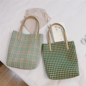 Détail du sac cabas vintage à carreaux verts avec anses en cuir et rivets en métal