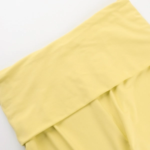 Close-up of light yellow knit fabric texture and folded material on white background