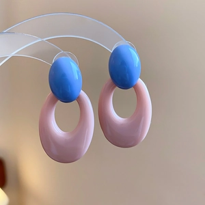 Macro shot of bicolour oval acrylic earrings in blue and pink on transparent stand